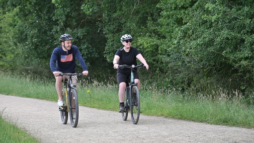 Two visitors cycling along a gravel path
